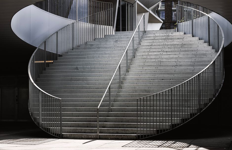 Two workers inside a residential property are engaged in the process of home relocation and furniture transport, specifically focusing on navigating a staircase. They are installing or securing a stai